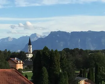 Blick auf eine Kirche und eine Bergkette unter blauem Himmel.