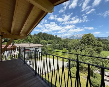 Geräumiger Balkon mit Holzboden und schmiedeeisernem Geländer, bietet einen weiten Blick auf die Berge.