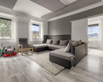 Helles Wohnzimmer mit großem Ecksofa, modernem Decken-Design und Blick ins Grüne.