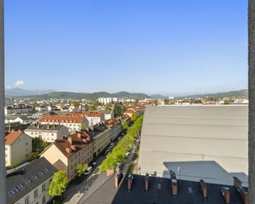 Panoramablick über die Stadt mit Bergen im Hintergrund an einem sonnigen Tag.