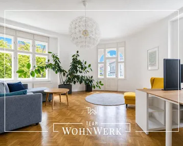 Helles Wohnzimmer mit Fischgrätparkett, großen Fenstern und Blick ins Grüne.