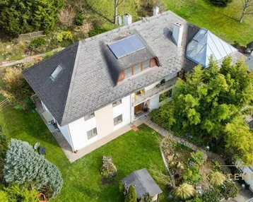 Luftaufnahme eines Hauses mit großem Garten, umgeben von viel Grün und Bäumen.