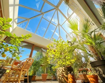 Heller Wintergarten mit Glasdach und vielen Pflanzen, ideal für entspannte Stunden und viel Tageslicht.