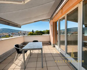 Geräumige Dachterrasse mit Markise, Esstisch und weitem Blick über die Stadt und Hügel.