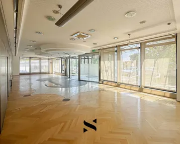 Geräumiger Bürobereich mit Fischgrätparkett, großen Fenstern und viel Tageslicht.
