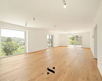 Geräumiges, helles Wohnzimmer mit Eichenparkettboden und großen Fenstern mit Blick ins Grüne.