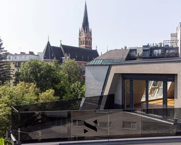 Moderne Dachterrasse mit Glasgeländer und Blick auf die Stadt und eine Kirche.