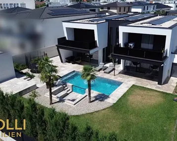 Moderne Villa mit Pool, Garten und Solaranlagen auf dem Dach in einer Wohnsiedlung.