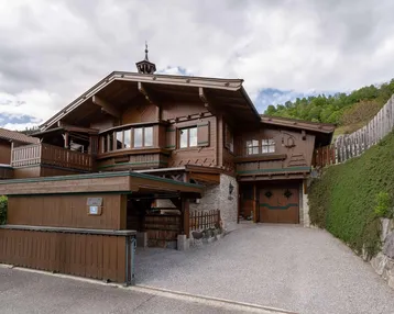 Traditionelles Holzhaus im alpinen Stil mit Garage und gepflegter Auffahrt.