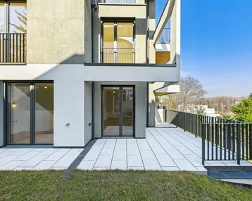 Moderne Terrasse mit hellen Fliesen, schwarzem Metallgeländer und Zugang zum Gartenbereich.