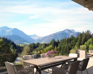 Großzügige Terrasse mit Esstisch und Lounge-Bereich, umgeben von einer beeindruckenden Berglandschaft.