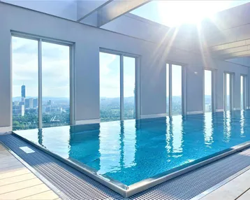 Heller Innenpool mit großen Fenstern und beeindruckendem Panoramablick auf die Stadt.