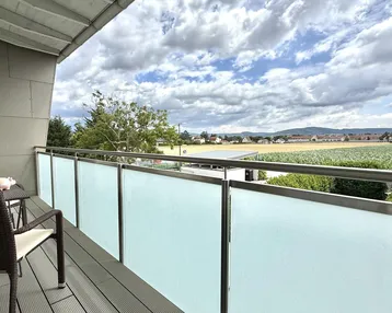 Balkon mit Sitzgelegenheiten und weitem Blick über Felder und die umliegende Landschaft.