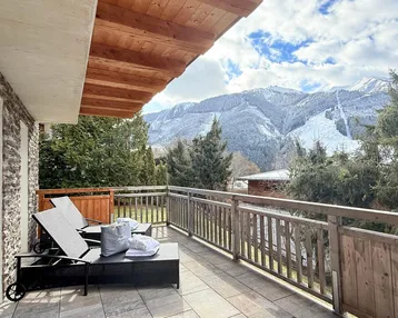 Geräumiger Balkon mit bequemen Liegestühlen und atemberaubendem Blick auf die schneebedeckten Berge.