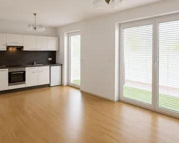 Helle, offene Küche mit weißen Schränken, Holzboden und Zugang zu großen Fenstern.
