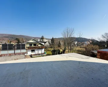 Panoramablick von der Baustelle auf die umliegende Wohngegend und grüne Hügel.