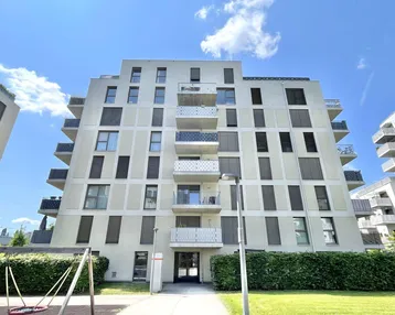 Moderne Wohnanlage mit mehreren Balkonen und einem kleinen Spielplatz im Vordergrund.