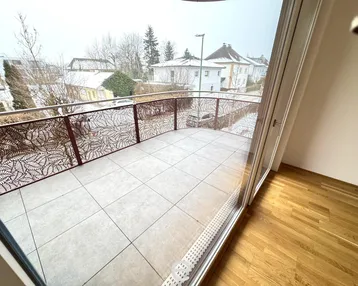 Balkon mit dekorativem Metallgeländer und Blick auf die verschneite Wohngegend.