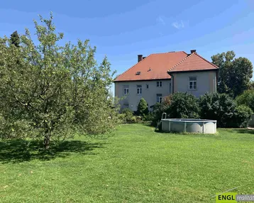 Großer Garten mit Rasenfläche, Obstbaum und einem Aufstellpool vor dem traditionellen Haus.