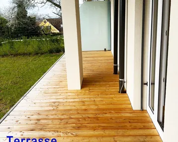 Geräumige Holzterrasse mit Blick ins Grüne, ideal für entspannte Stunden im Freien und Mahlzeiten.