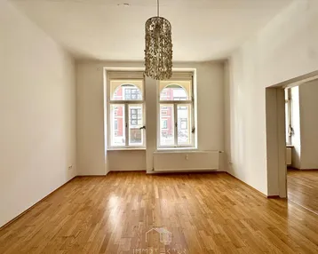 Helles, leeres Zimmer mit Parkettboden und zwei hohen Bogenfenstern, bereit zur individuellen Gestaltung.
