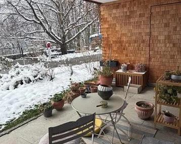 Überdachte Terrasse mit Sitzgelegenheiten und Blick auf eine verschneite Winterlandschaft.
