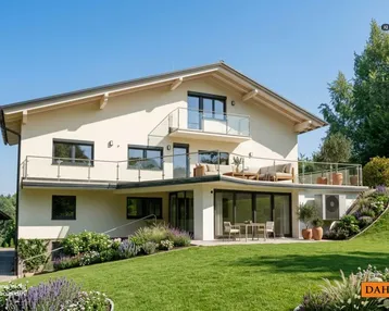 Modernes Haus mit mehreren Balkonen, einer Terrasse und gepflegtem Gartenbereich.