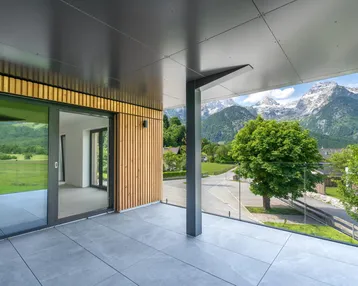 Moderner Balkon mit Fliesenboden, Holzverkleidung und atemberaubendem Bergblick.