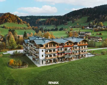 Modernes Mehrfamilienhaus in alpiner Landschaft mit Balkonen und Bergblick.