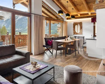 Gemütlicher Wohn- und Essbereich im alpinen Stil mit Kamin und Bergblick sowie Balkonzugang.