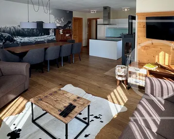 Heller Wohnbereich mit bequemen Sofas, Holzboden und Blick auf den Ess- und Küchenbereich.
