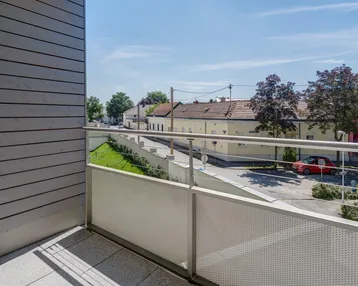 Heller Balkon mit Blick auf die Straße und umliegende Häuser, ideal für entspannte Stunden im Freien.