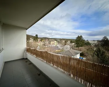 Geräumiger Balkon mit Fliesenboden und weitem Blick über die grüne Umgebung.