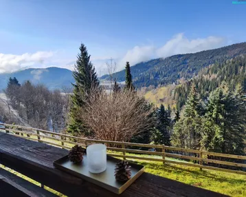 Balkon mit rustikalem Holzgeländer und weitem Blick auf die umliegende Berglandschaft.