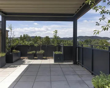 Geräumige Dachterrasse mit Pergola, Fliesenboden und weitem Ausblick.