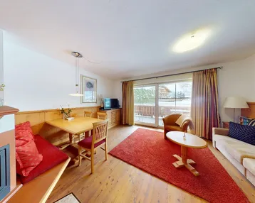 Gemütlicher Wohn- und Essbereich mit Kamin, Holzboden und Zugang zum Balkon.