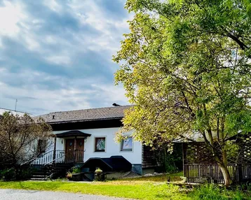 Traditionelles Einfamilienhaus mit weißer Fassade, dunklem Dach und gepflegtem Vorgarten.