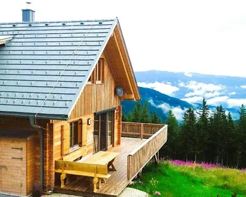 Rustikales Holzhaus mit großer Terrasse und atemberaubendem Bergblick in alpiner Umgebung.