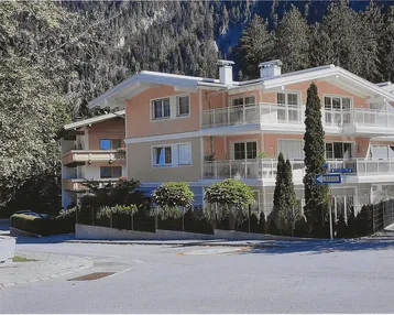 Modernes Mehrfamilienhaus mit mehreren Balkonen und gepflegter Fassade in alpiner Umgebung.