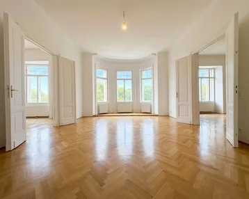 Großzügiges, helles Zimmer mit Fischgrätparkett und vielen Fenstern, das vielseitig nutzbar ist.