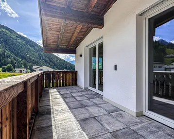 Geräumiger Balkon mit Fliesenboden, Holzgeländer und herrlichem Bergblick in die Natur.