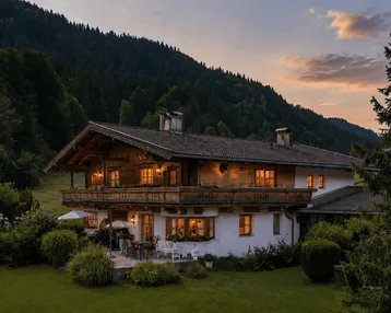 Großes Chalet im alpenländischen Stil mit Terrasse, Garten und Bergblick bei Sonnenuntergang.