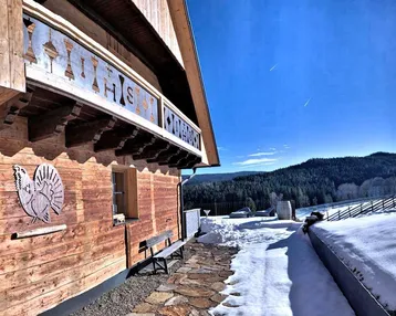 Winterliches Holzchalet mit weitem Blick auf die verschneite Landschaft und Skipisten.