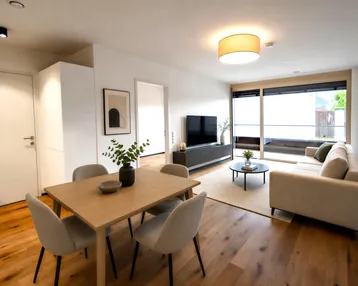 Heller Wohn- und Essbereich mit modernem Mobiliar, Holzboden und Zugang zu einem Balkon.