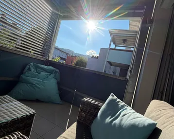 Sonniger Balkon mit bequemen Outdoor-Möbeln und Blick auf die Berge.
