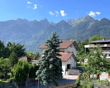 Panoramablick auf die umliegende Berglandschaft mit Wohnhäusern und viel Grün.