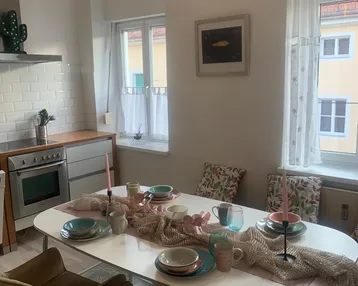 Helle Wohnküche mit Esstisch, modernen Geräten und Blick nach draußen.