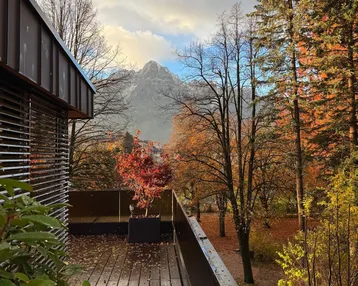 Geräumiger Balkon mit Holzboden und herbstlicher Bepflanzung, bietet einen atemberaubenden Blick auf die Berge.