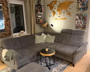 Gemütliches Wohnzimmer mit großem Ecksofa, Holzboden und dekorativer Weltkarte an der Wand.