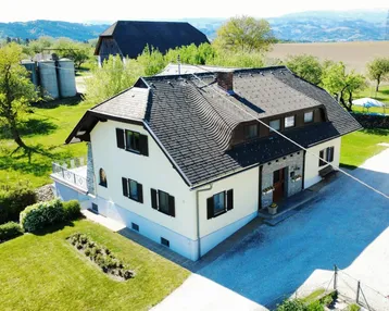 Freistehendes Haus mit komplexem Dach und weitläufigem Grundstück in ländlicher Umgebung mit Bergblick.